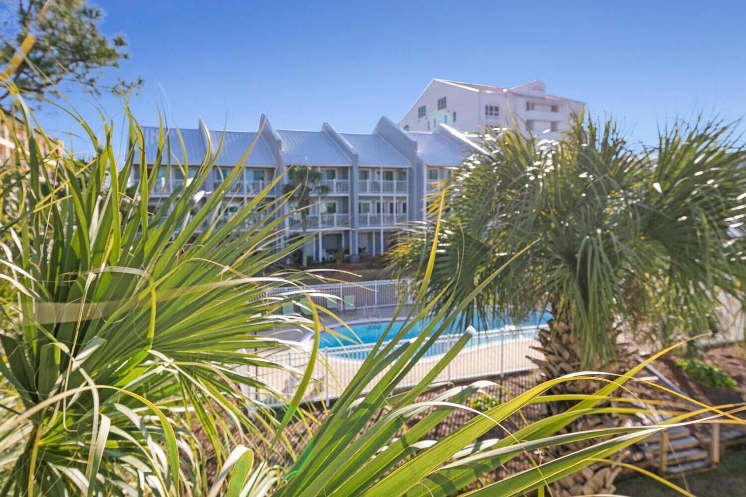 Ein Hotel mit Pool, umgeben von Palmen und blauem Himmel.