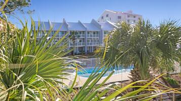Ein Hotel mit Pool, umgeben von Palmen und blauem Himmel.
