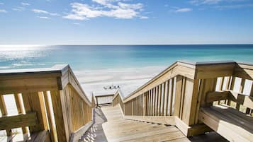 Eine Holzterrasse führt zu einem Strand mit freiem Blick auf das Meer.