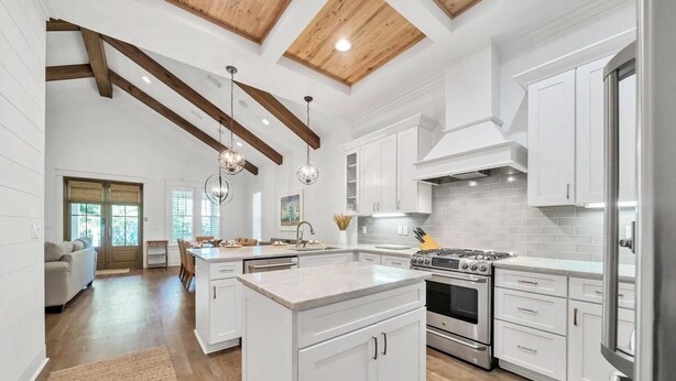 Une cuisine spacieuse avec des meubles blancs, un îlot central et une grande cuisinière.