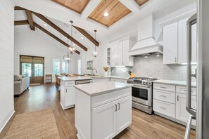 A spacious kitchen with white cabinetry, a central island, and a large stove. - Peaceful Easy Feeling (Santa Rosa Beach)
