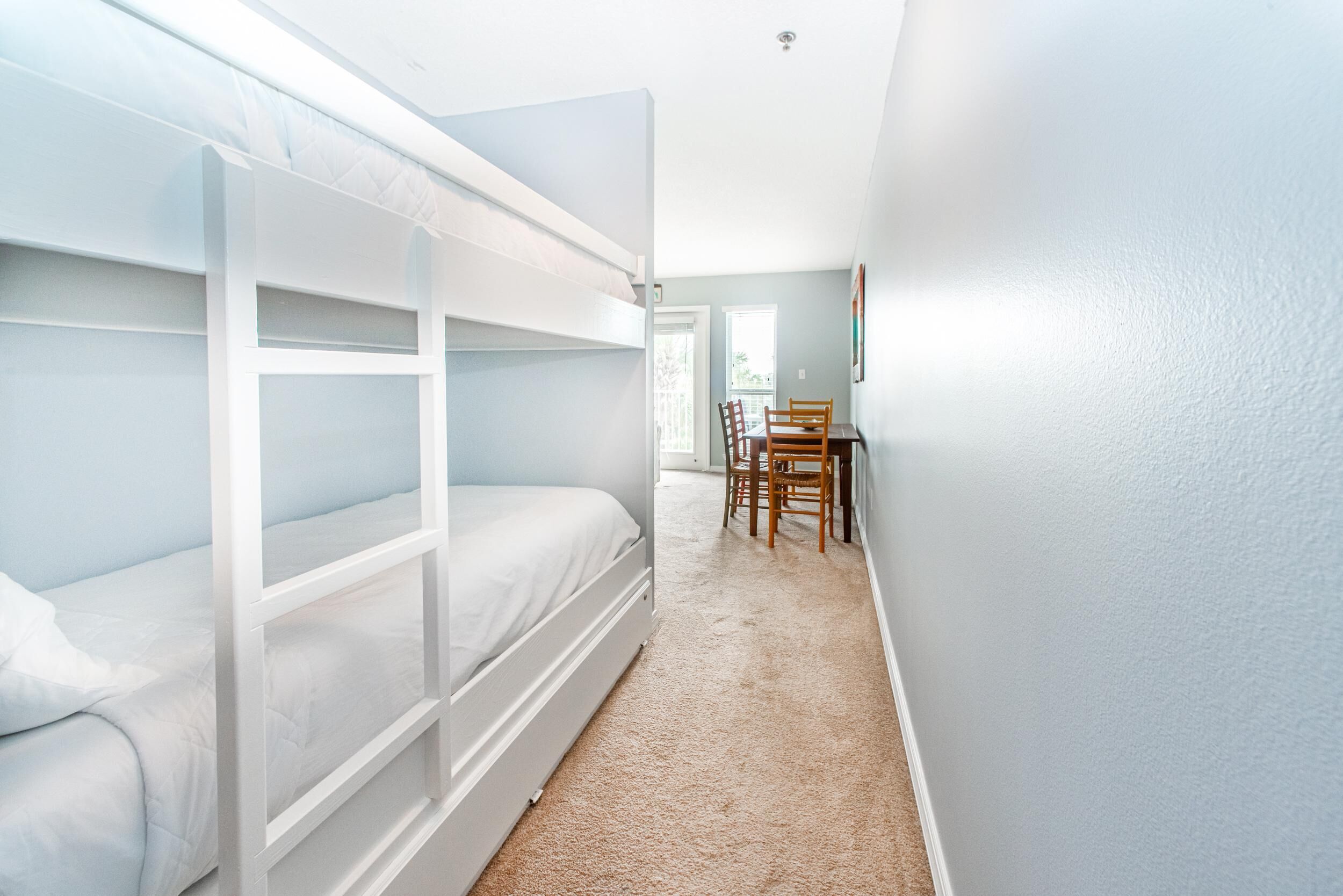 A room with bunk beds, a dining table, and chairs.