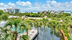A resort with a pool surrounded by palm trees, a view of the ocean, and a modern building in the background. - Gulf Place Cabanas 410- Gulf Place Getaway (Santa Rosa Beach)