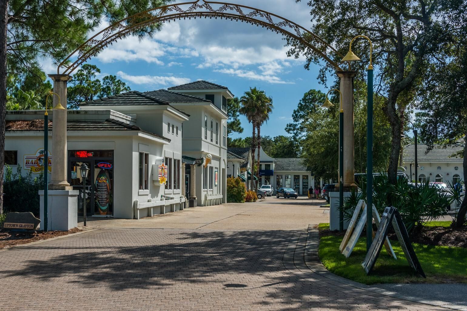 A street view with a row of two-story buildings, a clear sky, and a paved road.