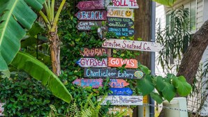 A wooden signpost with various colorful signs pointing to local attractions and businesses.