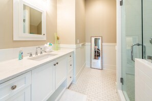 A modern bathroom with a white vanity, a large mirror, and a glass shower enclosure. - Day Is Done (Santa Rosa Beach)