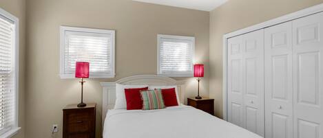 A bedroom with a bed, two bedside tables, a ceiling fan, and a wardrobe.
