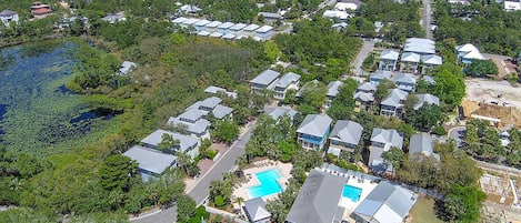 Vue aérienne d’un quartier résidentiel comprenant plusieurs maisons, une piscine et une étendue d’eau.