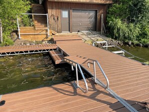 A wooden dock leading to a house with a garage.