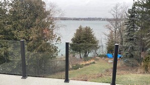 A view from a balcony overlooking a lake with trees and a distant shoreline. - Relax and Rejuvinate at the cottage.  Get some forest therapy. (Bridgenorth)