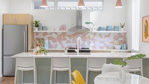Eine moderne Küche mit einer zentralen Kochinsel, Pendelleuchten und einer geometrischen Spritzschutzwand.