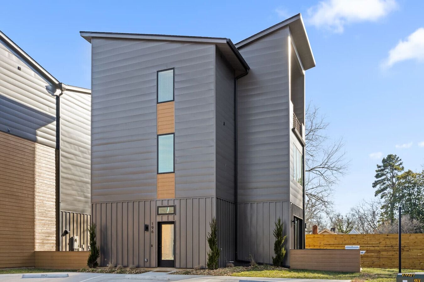 Un edificio moderno dal design angolare originale, caratterizzato da ampie finestre e un pannello verticale in legno ben visibile.