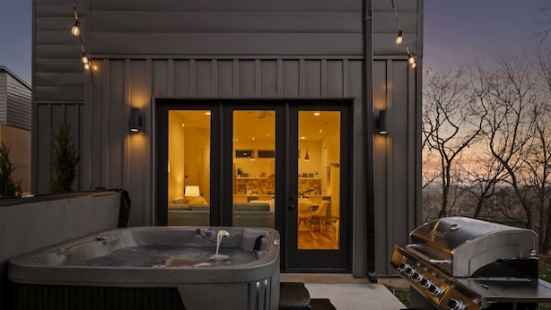 Ein Whirlpool, ein Grillplatz im Freien und der Blick auf ein Haus mit einer Schiebetür.