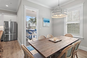 A dining area with a wooden table, wicker chairs, and a modern chandelier. - Blue Mountain RNR (Santa Rosa Beach)