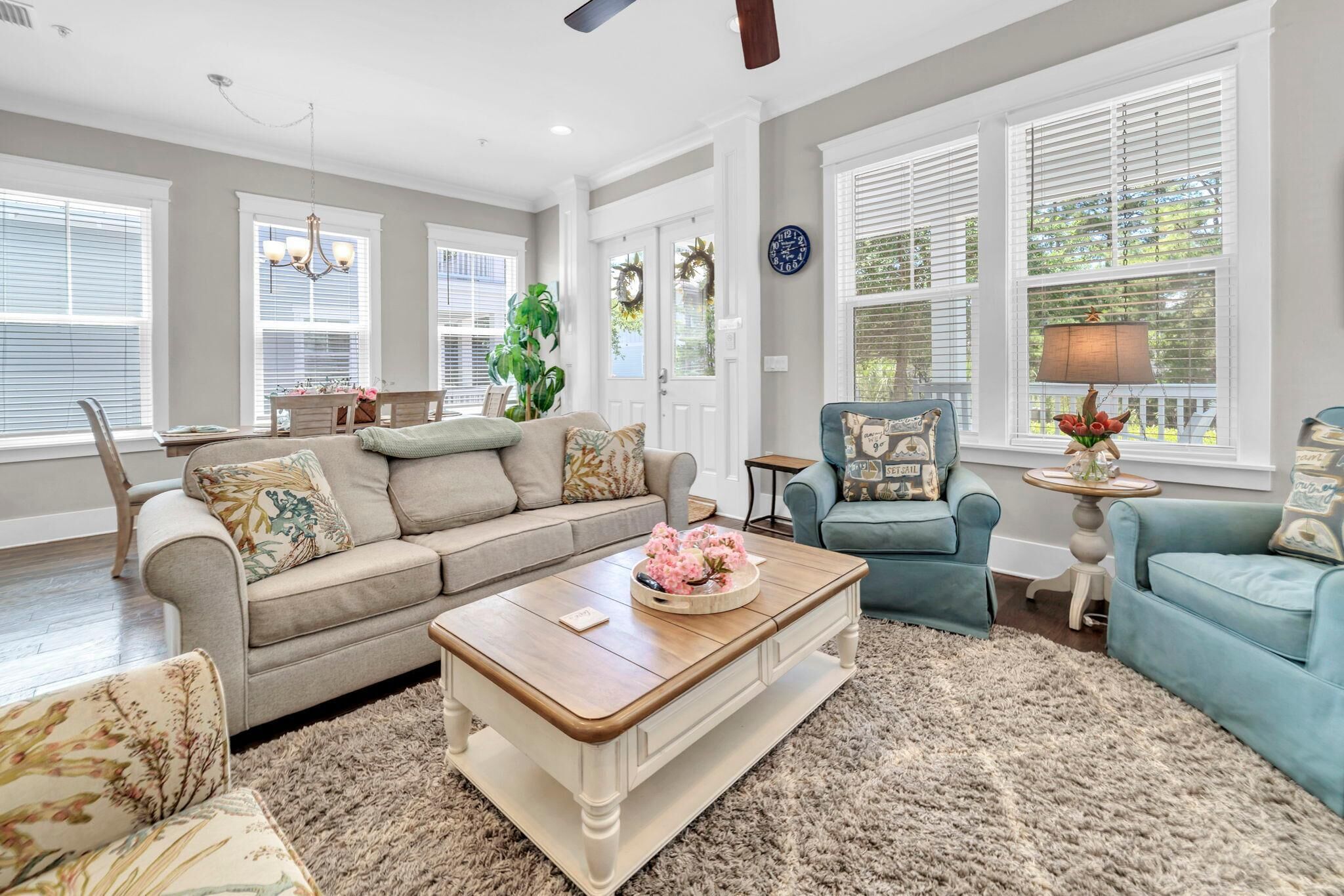 A living room with a sofa, two armchairs, a coffee table, and a chandelier.
