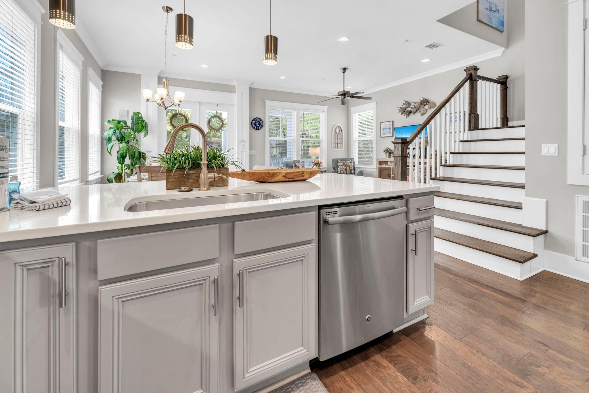 A spacious kitchen with a large island, stainless steel dishwasher, and a wooden bowl centerpiece.
