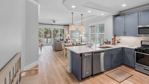 A modern kitchen with a central island, built-in appliances, and a view to a dining area. - Adagio F205 (Santa Rosa Beach)