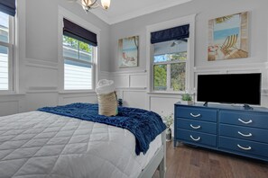 A bedroom with a bed, a dresser, a TV, and artwork on the walls. - 30A Sunshine Shack (Santa Rosa Beach)