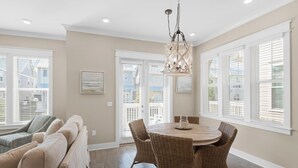 A dining area with a round table and wicker chairs, a sofa, and a hanging light fixture. - Town of Prominence 326b- Seaside Paradise (Santa Rosa Beach)