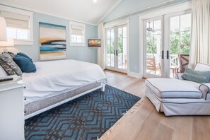 A bedroom with a large bed, a sofa, and a view of the outdoors through a sliding glass door. - The Nautilus (Santa Rosa Beach)