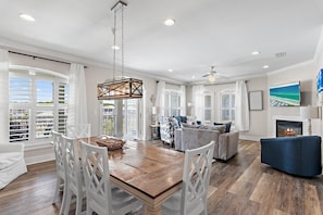 A spacious living area with a dining table, white chairs, a blue sofa, and a fireplace. - The Blue Lagoon (Panama City Beach)