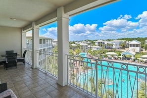 A balcony with a view of a swimming pool and resort buildings.
