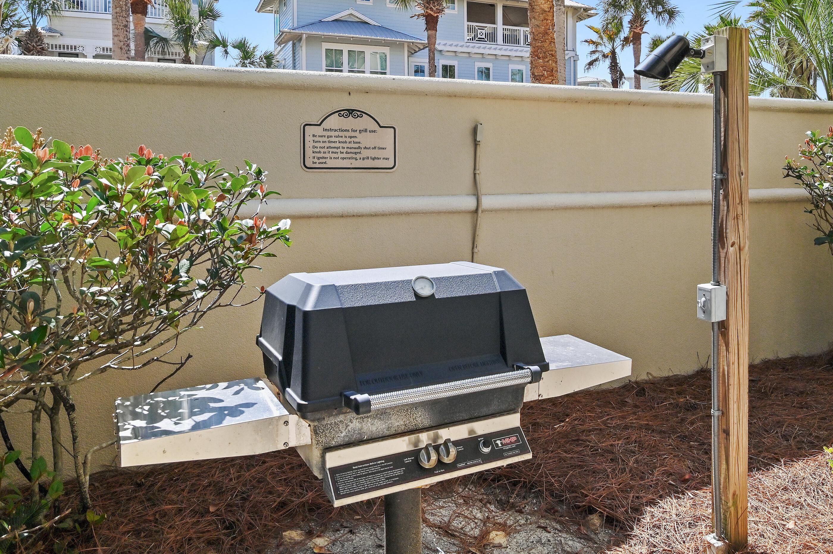 A barbecue grill with a control panel, a sign with instructions, and a wooden post.