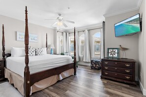 Ein Schlafzimmer mit einem Himmelbett, einem Deckenventilator, einem Fernseher und einer Kommode.