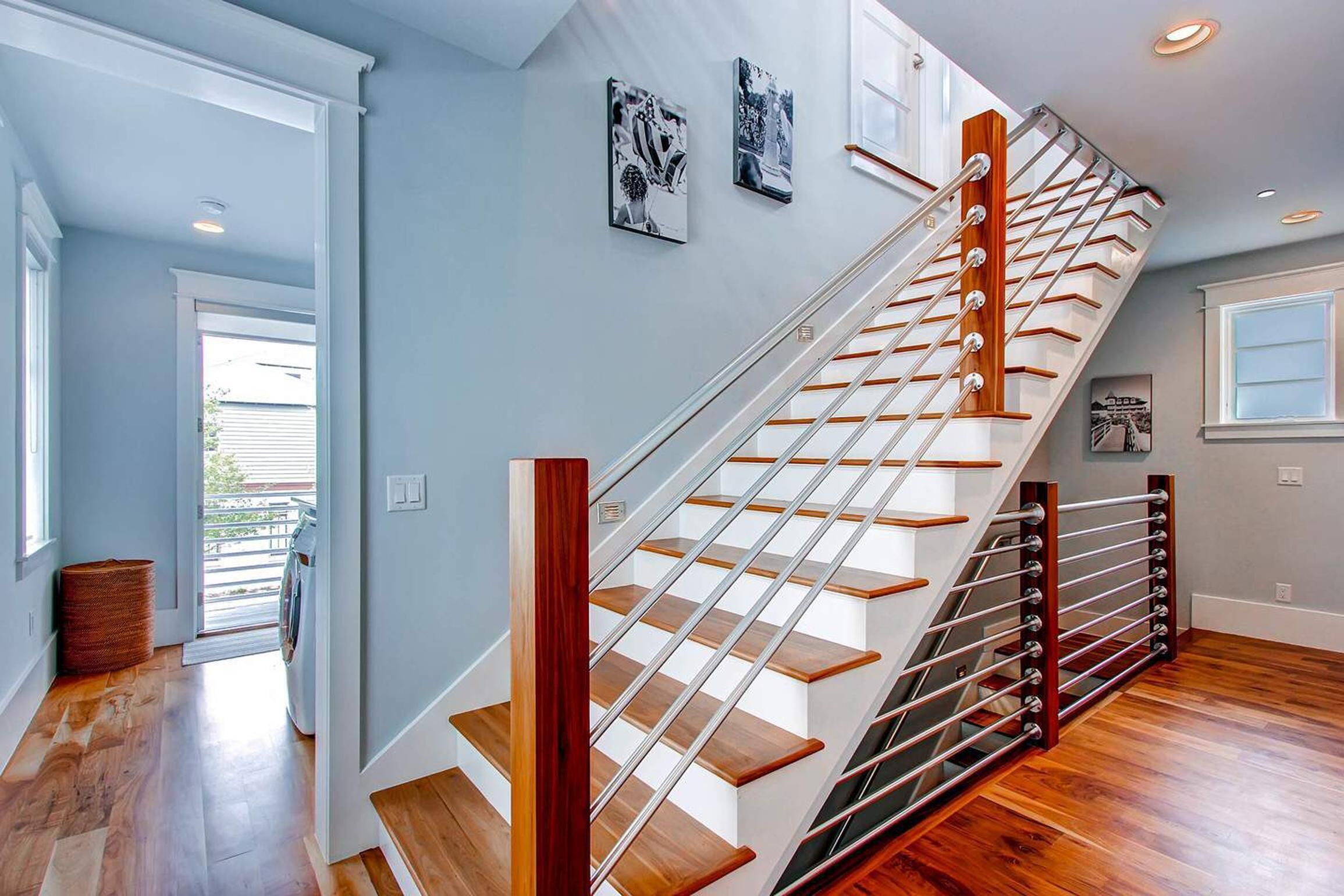 A modern staircase with wooden steps and metal railings, leading to an upper floor.