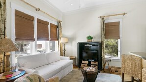 A living room with a white sofa, a television, and a small table with a lamp. - Sunsets at Rosemary Carriage House (Panama City Beach)