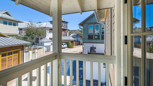 A covered porch with a view of a residential area, including houses and a small building. - Sunsets at Rosemary Carriage House (Panama City Beach)