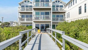 A multi-story beachfront building with a wooden walkway leading to the entrance. - Ramsgate 3 (Panama City Beach)