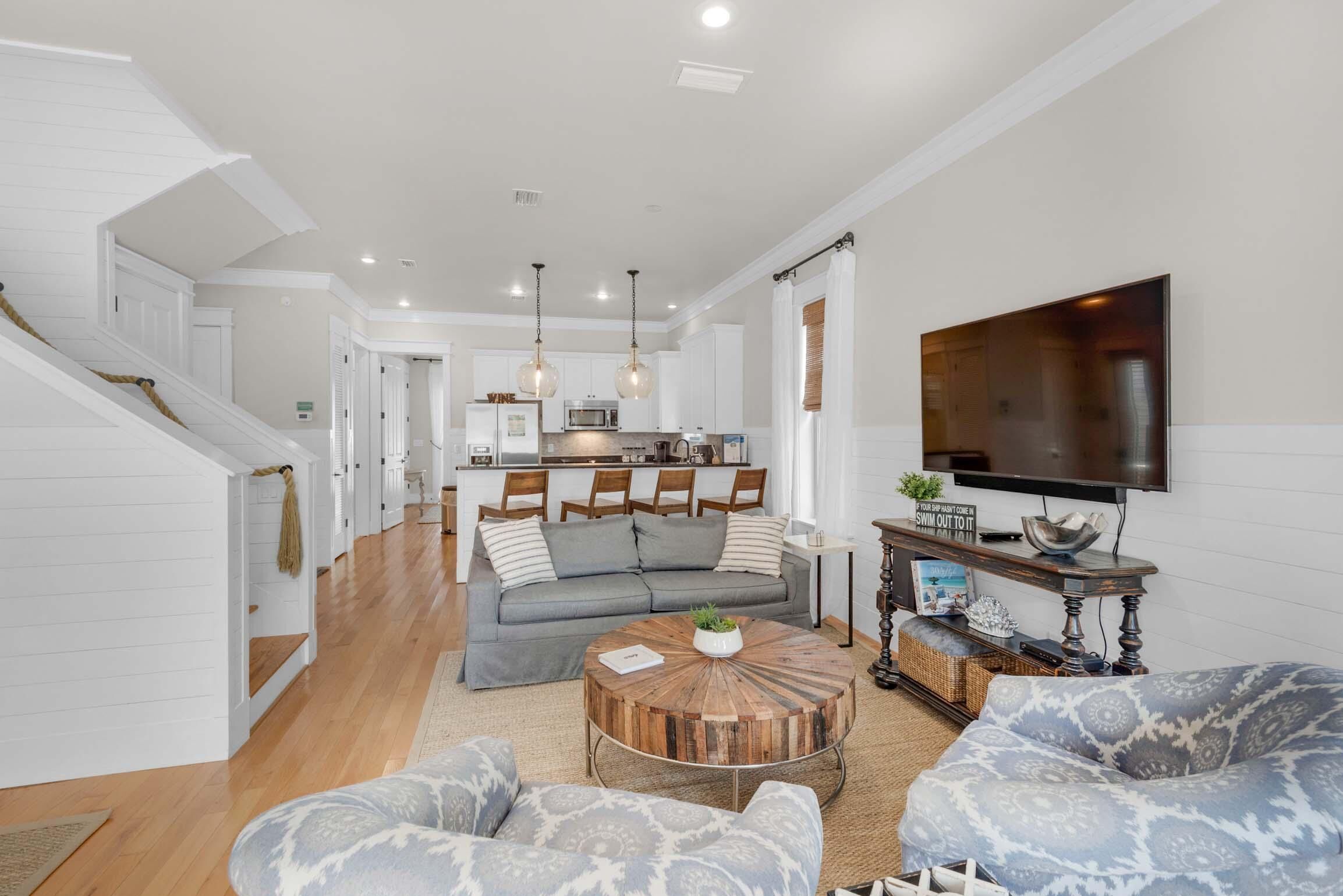 A spacious living area with a sofa, a coffee table, and a television mounted on the wall.
