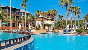 A resort with a large swimming pool, palm trees, and multiple-story buildings with balconies. - Daze Gone Bye (Panama City Beach)