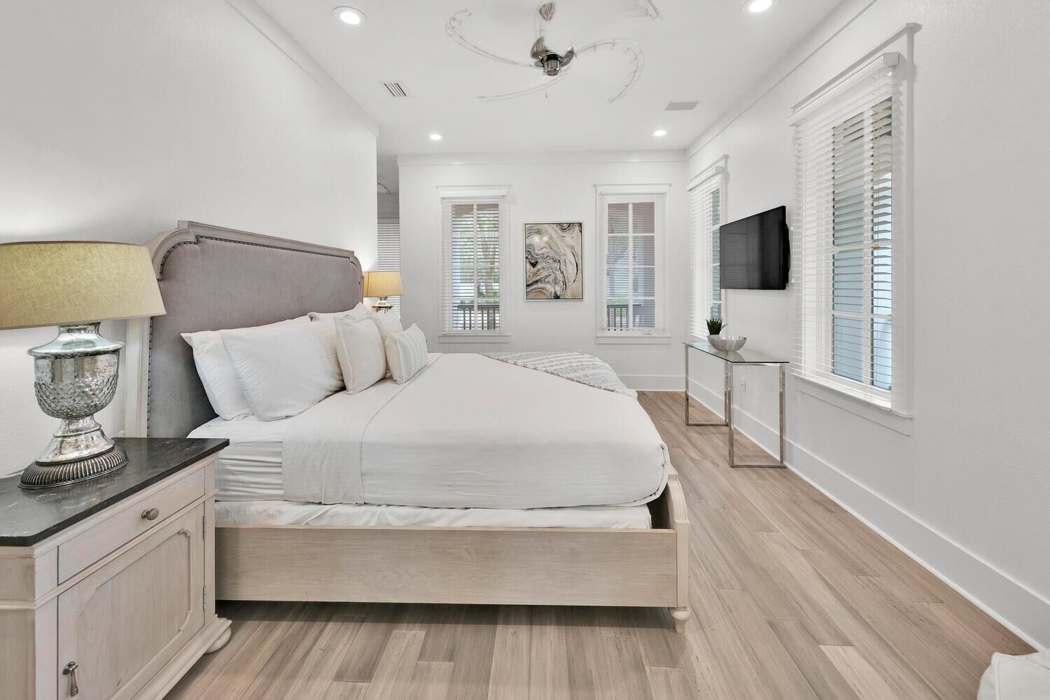 A bedroom with a bed, bedside table, lamp, and a TV on a stand.