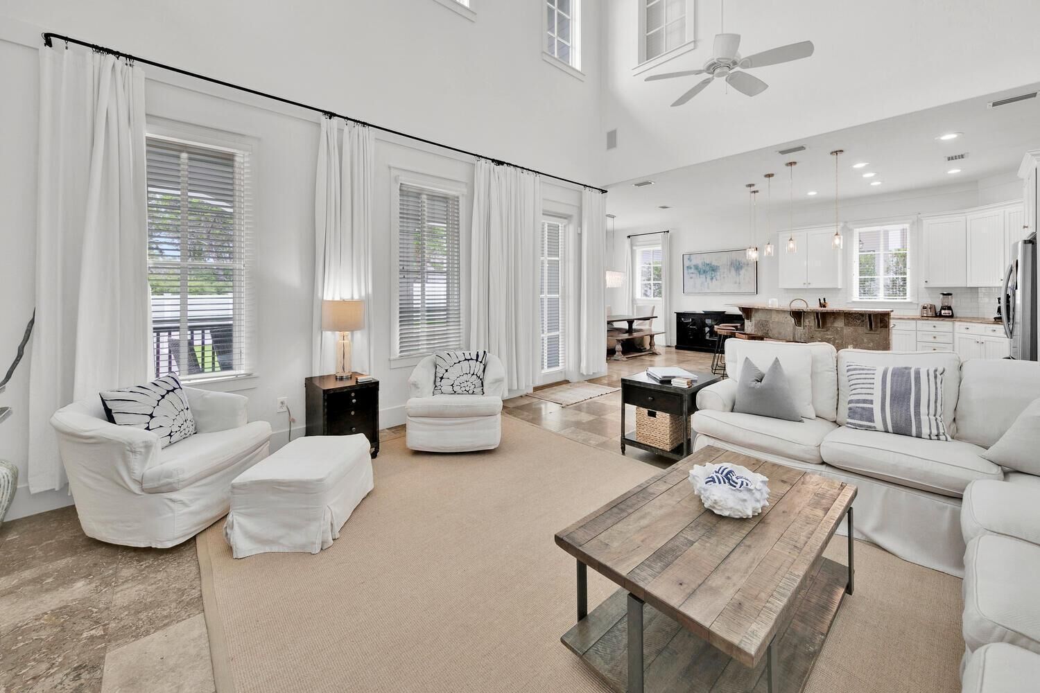 A spacious living room with a large sofa, a coffee table, and a dining area with a kitchen in the background.