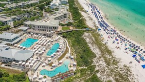 An aerial view of a coastal resort with multiple swimming pools, beach umbrellas, and a sandy beach. - The Retreat 1848 (Santa Rosa Beach)
