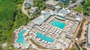 An aerial view of a resort with multiple swimming pools, sun loungers, and a covered area with umbrellas. - The Retreat 1848 (Santa Rosa Beach)