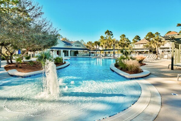 A swimming pool with a central fountain, surrounded by palm trees and lounge chairs. - Sunny Side Up (Santa Rosa Beach)