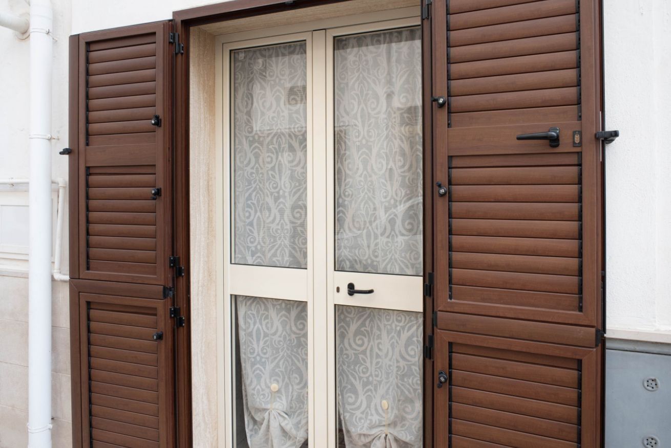 Una porta doppia con un pannello di vetro decorato e un telaio in legno.