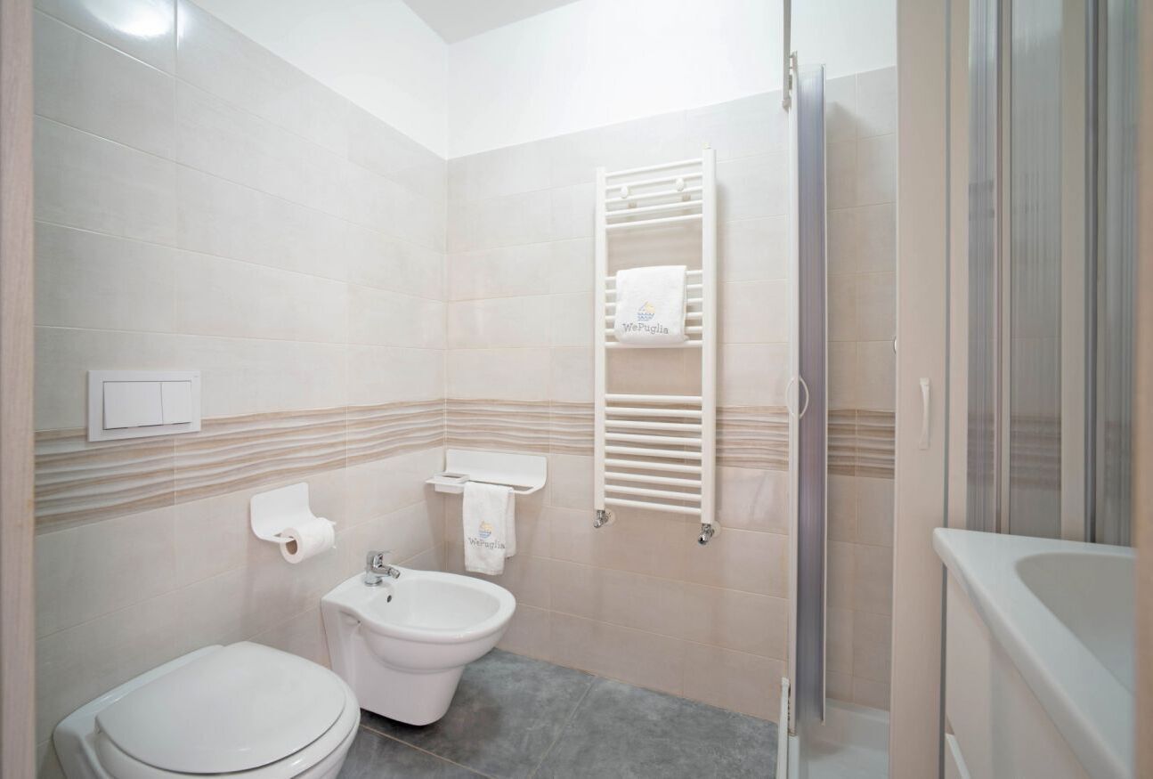Et badeværelse med toilet, bidet, håndklædetørre og bruseområde.