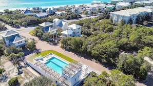 An aerial view of a coastal residential area with houses, a swimming pool, and a beach in the background. - Stay Salty (Santa Rosa Beach)