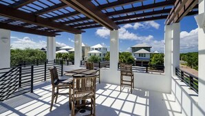 An outdoor patio with wooden furniture and a pergola structure. - Stay Salty (Santa Rosa Beach)