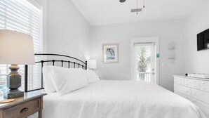 Un dormitorio con cama, mesita de noche, lámpara y ventana con persianas.
