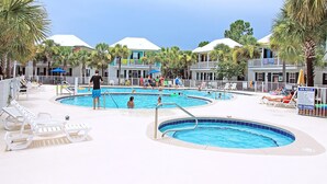 Un área de piscina con varias piscinas, sillas de descanso y palmeras.