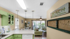 A kitchen with green cabinets, a white countertop, and a ceiling fan. - Rollin Tide Villas- Rollin Tide B9 (Santa Rosa Beach)