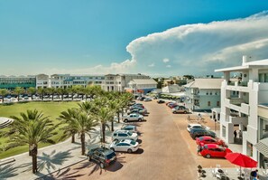 A hotel with a parking lot, palm trees, and a clear sky. - Rollin Tide Villas- Rollin Tide B9 (Santa Rosa Beach)