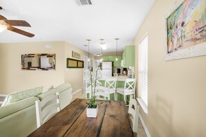 A dining area with a wooden table, white chairs, and a potted plant. - Rollin Tide Villas- Rollin Tide B9 (Santa Rosa Beach)