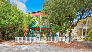A building with a green roof and a white fence in front. - Playhouse II (Santa Rosa Beach)