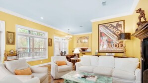 A living room with striped sofas, a coffee table, and a piano-themed artwork on the wall. - Playhouse II (Santa Rosa Beach)